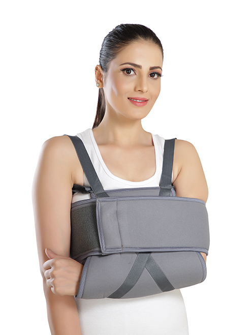 Person wearing a shoulder immobilizer to restrict shoulder and upper arm movement after injury or surgery.